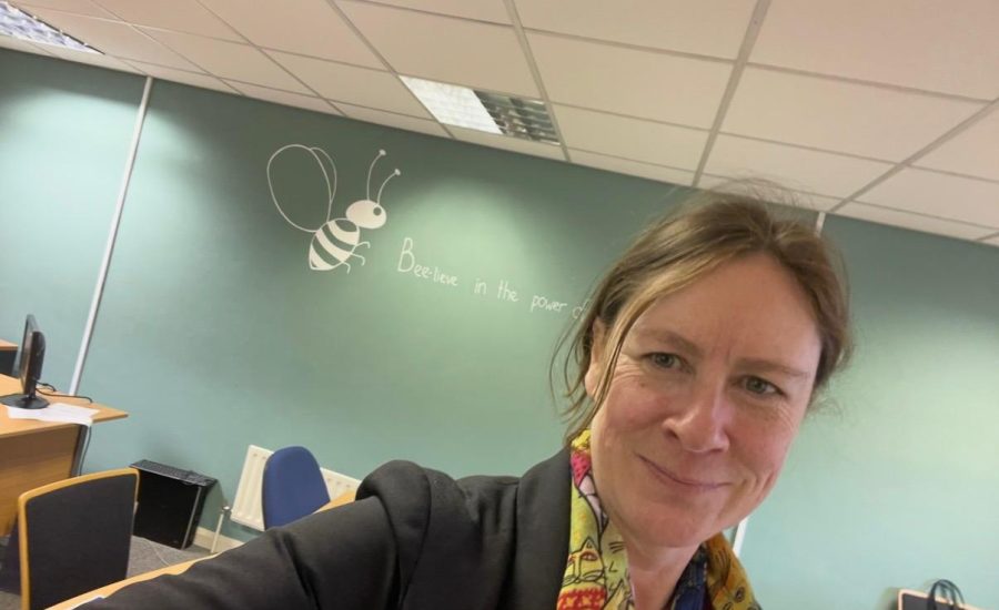 Tracey in the office with typically messy hair and the Arctic Bee logo behind her